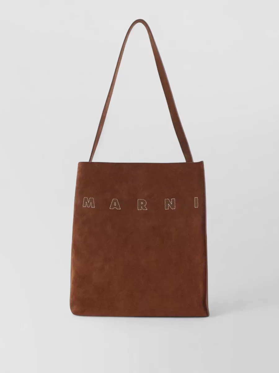 Marni museo small leather tote bag — The chestnut suede shoulder tote picks up the mule’s espresso patches and adds rich texture without disturbing the neutral palette, keeping the outfit coherent and polished-casual.