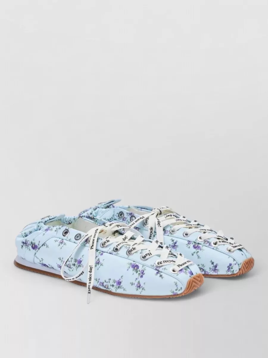 Ganni Lace up sporty ballerinas — The floral sky-blue lace-up flats echo the pastel logo tones on the tee and keep the mood playful yet streetwear-appropriate with their slim, sneaker-adjacent profile.