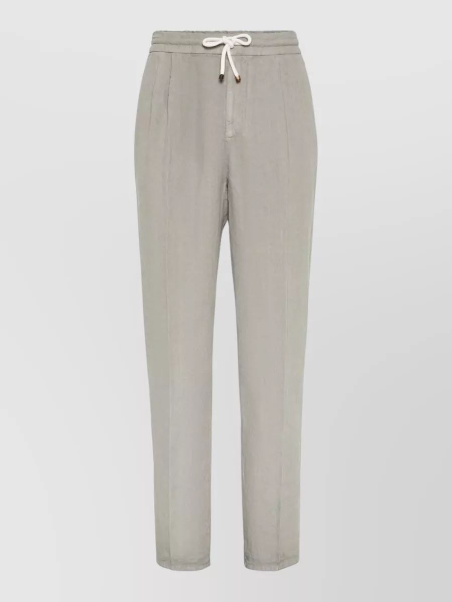 Brunello Cucinelli Linen tapered drawstring trousers — The Row’s mid‑indigo straight jean keeps the outfit relaxed and quiet with a subtle contrast to the navy knit, staying in the same brand universe and matching the soft, clean silhouette.