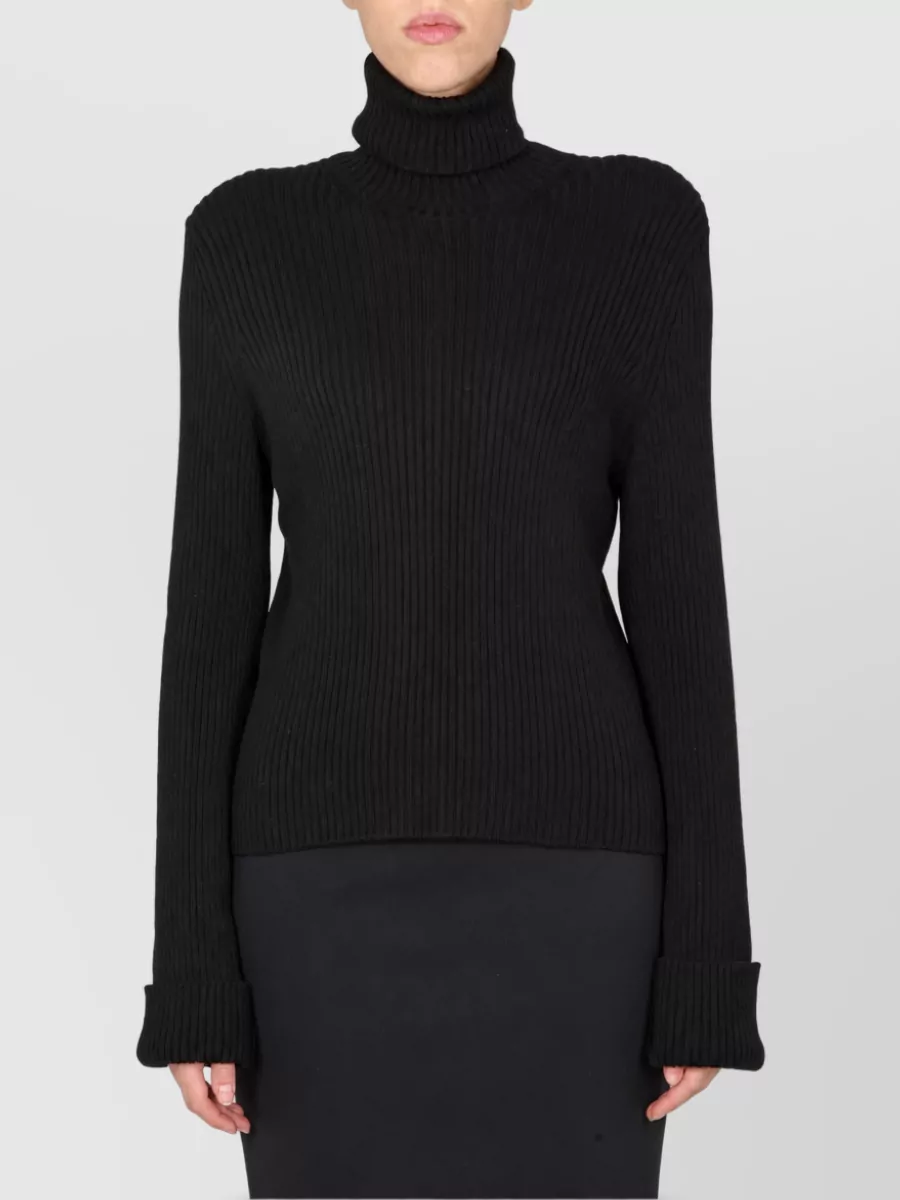 Balenciaga Turtleneck sweatshirt — The fitted black ribbed turtleneck tucks cleanly into the high-waisted pleated skirt, echoing its quiet-luxury mood while balancing the volume with a sleek, elongated upper body.