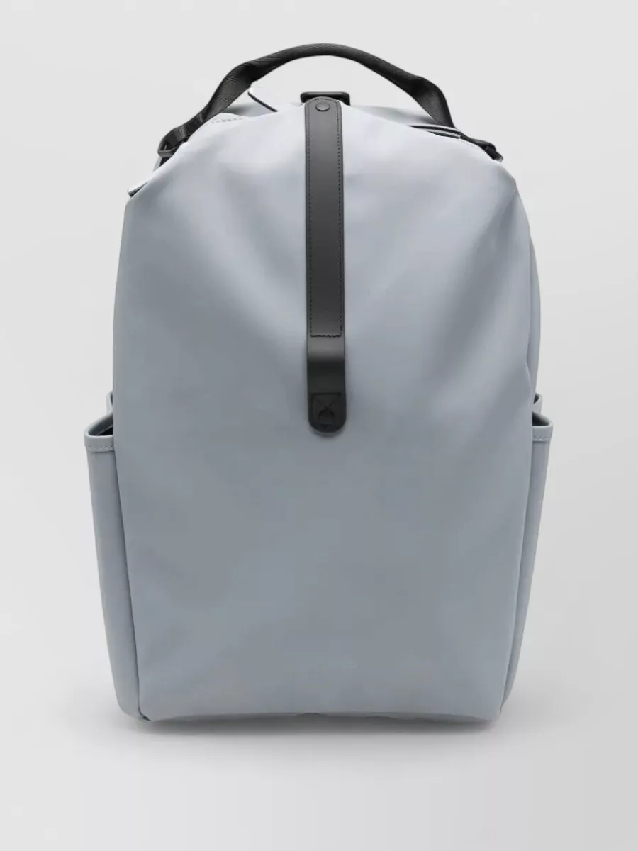 Rains Backpack — The A.P.C. indigo denim tote adds just enough structure and contrast to the pale Polo palette, still reading casual but refined with navy and tan that complement preppy blue and white.