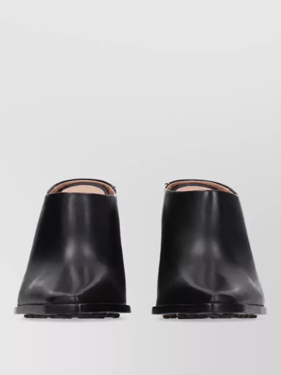 Bottega Veneta Leather mules — The black block-heel mules are minimal, structured and suitably dressy, grounding the ivory trouser and black tank in a polished, architectural way that matches the Bottega language.