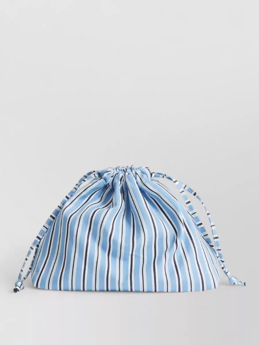The Frankie Shop Striped bucket bag — Furla’s structured powder-blue shoulder bag keeps the palette soft and tonal while adding just enough quiet structure to balance the relaxed short and shirt combo.