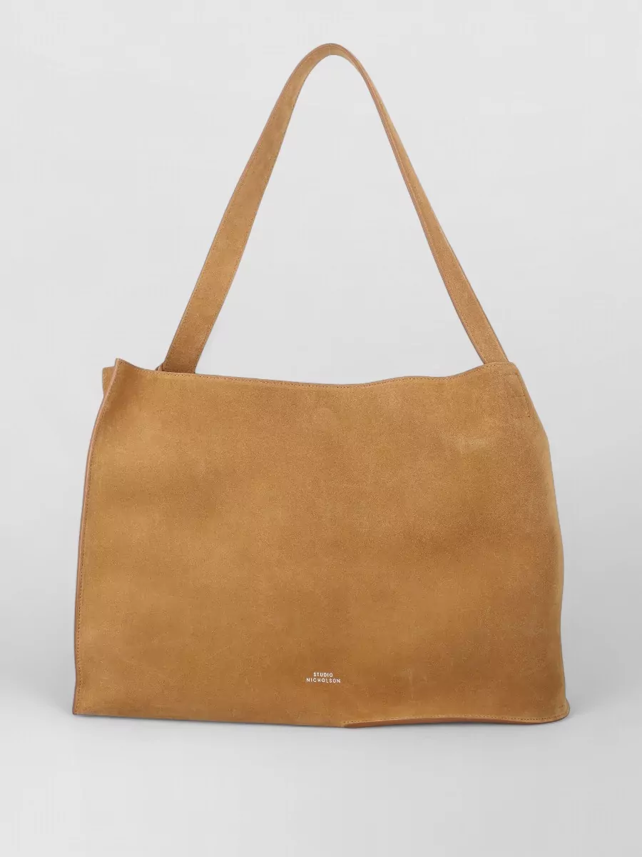 Studio Nicholson Leather shoulder bag — The camel Studio Nicholson suede tote adds warm texture and quiet utility, aligning with the dress’s relaxed city uniform mood without disrupting its minimalist attitude.