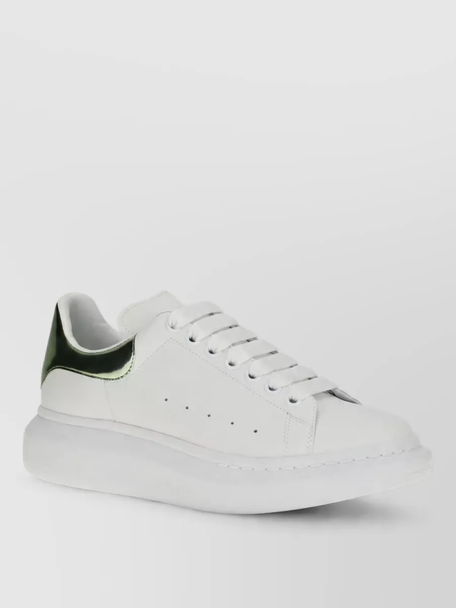Alexander McQueen Leather platform sneakers — Alexander McQueen’s chunky white sneaker with metallic forest green heel quietly echoes the tee’s green base while giving a clean, modern streetwear anchor that works perfectly with the cargo short length.