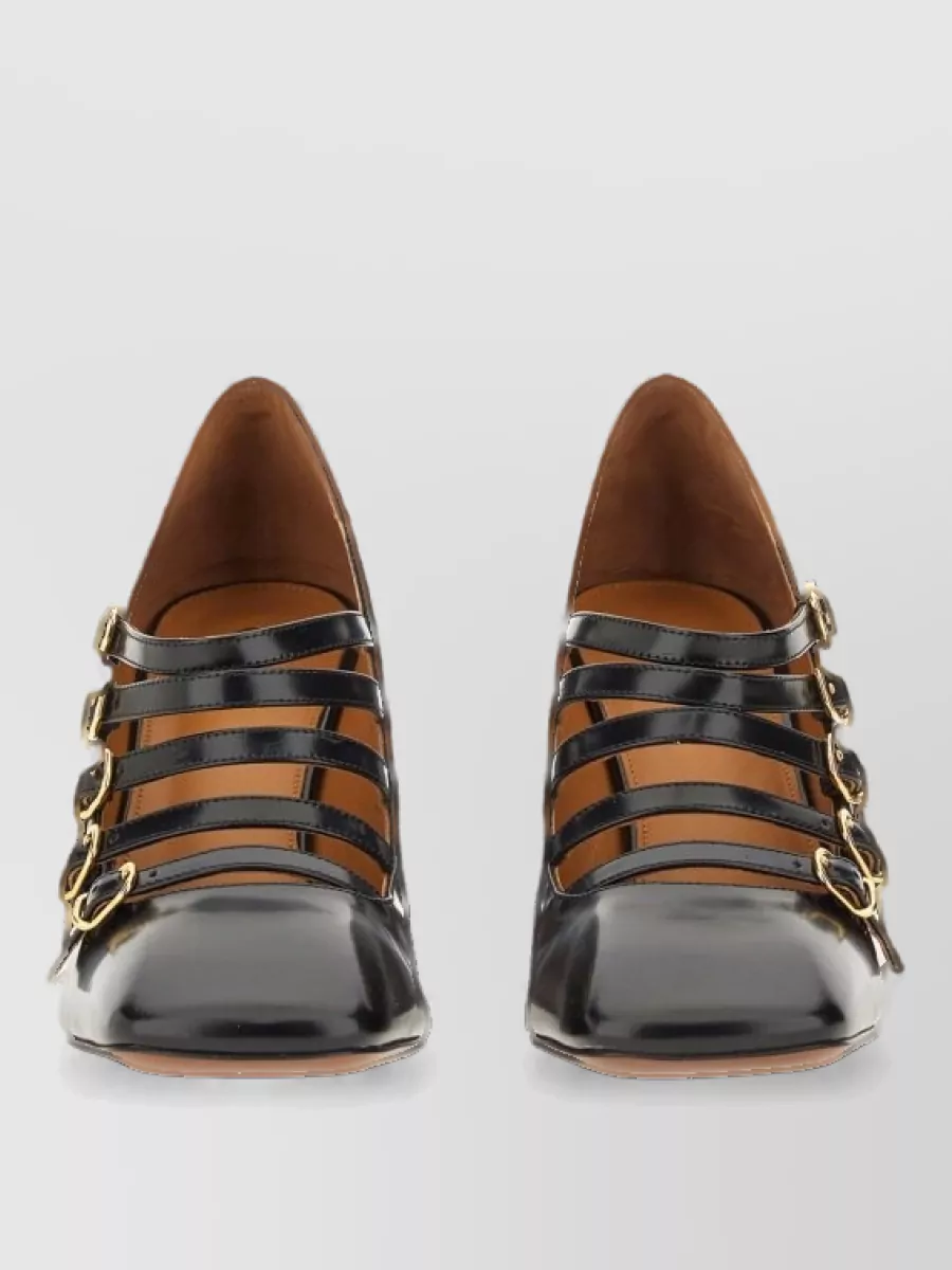 Chloé Leather pumps — The black sculpted block-heel pumps with gold hardware introduce a grounded, dressy contrast that sharpens the romantic blouse and wide-leg trouser while remaining in the same tailored luxury tier.