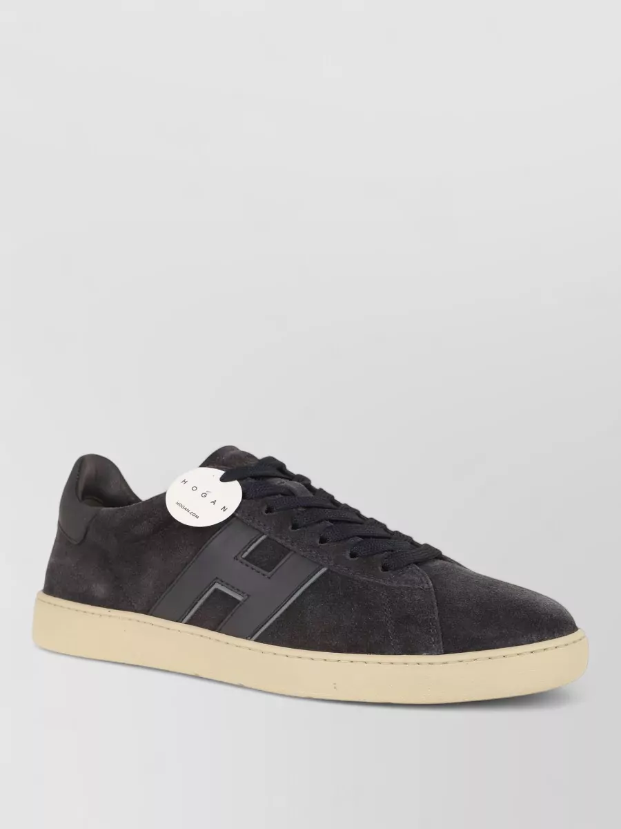 Hogan Leather low-top sneakers — The soft-white Hogan cupsole sneaker is minimalist and quietly luxurious, bridging the black polo and navy shorts with a clean light base that feels polished yet relaxed for summer.