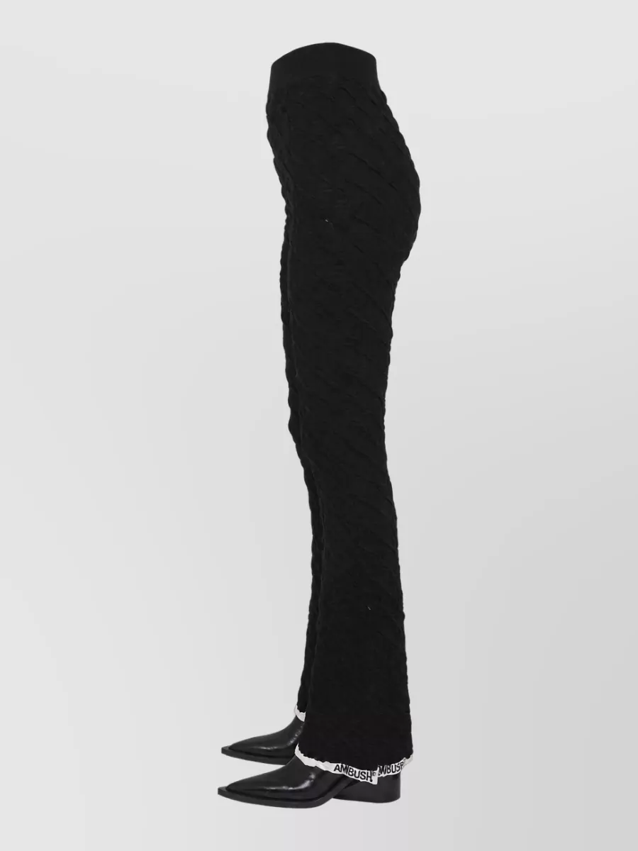 Ambush Logo flared trousers — The sculpting black Ambush flares with the contrast logo cuff mirror the brand, keep the y2k street tailoring energy, and balance the cropped mesh top with a long, leggy line.