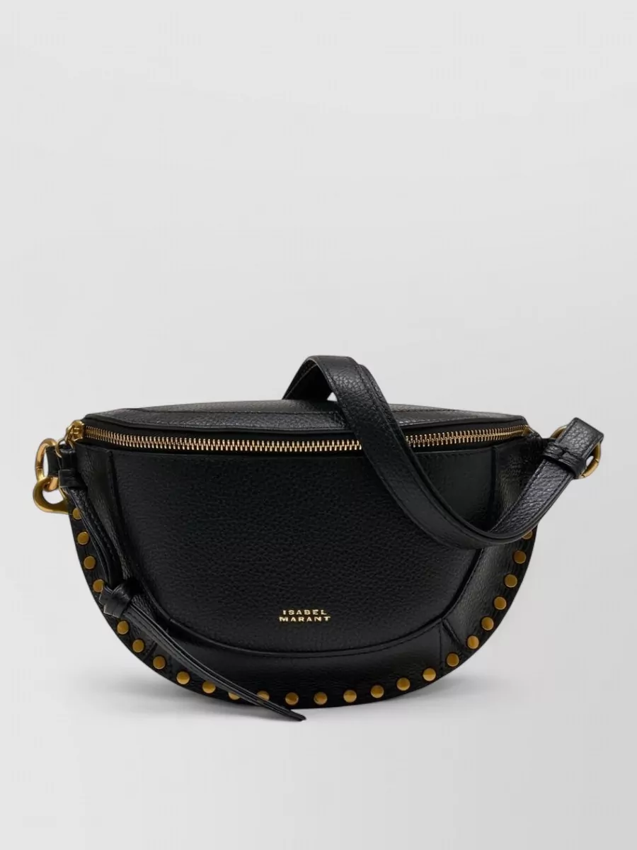 Isabel Marant skano hammered leather belt bag with studs — The black studded saddle crossbody hits the same Isabel Marant rock-boho note as the boots and sweatshirt, staying compact and structured so it does not fight the volume of the jeans.