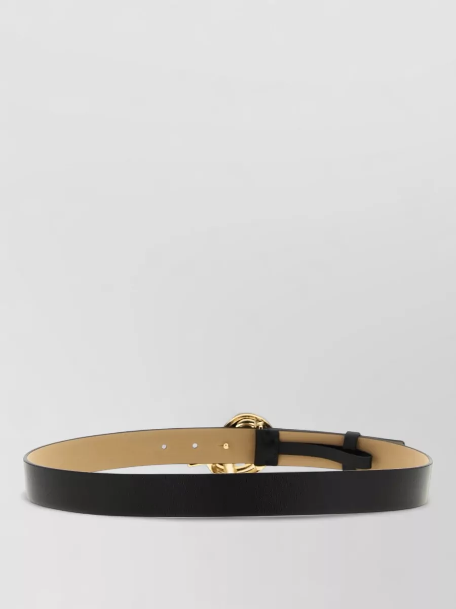 Fabiana Filippi Leather knot buckle belt — The slim black Fabiana Filippi belt with a refined gold buckle subtly defines the waist over the trouser without adding more logo drama, keeping the focus on the jacket’s zips.
