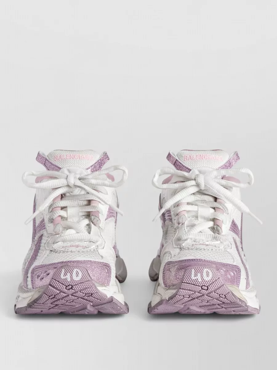 Balenciaga Glitter low-top sneakers — The white and lilac chunky runners pick up the soft pink of the tee in a cooler tone and their sculpted profile matches Balenciaga’s athletic, oversized streetwear language from head to toe.