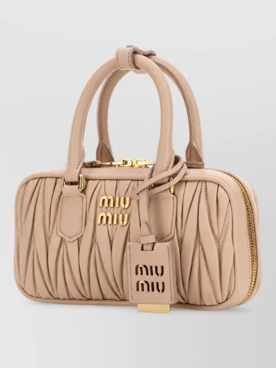 Miu Miu arcadie nappa leather clutch bag — The nude-blush mini top-handle keeps the mood soft and feminine, harmonising with the ivory dress and flats while staying refined enough to take the piece beyond the bedroom.