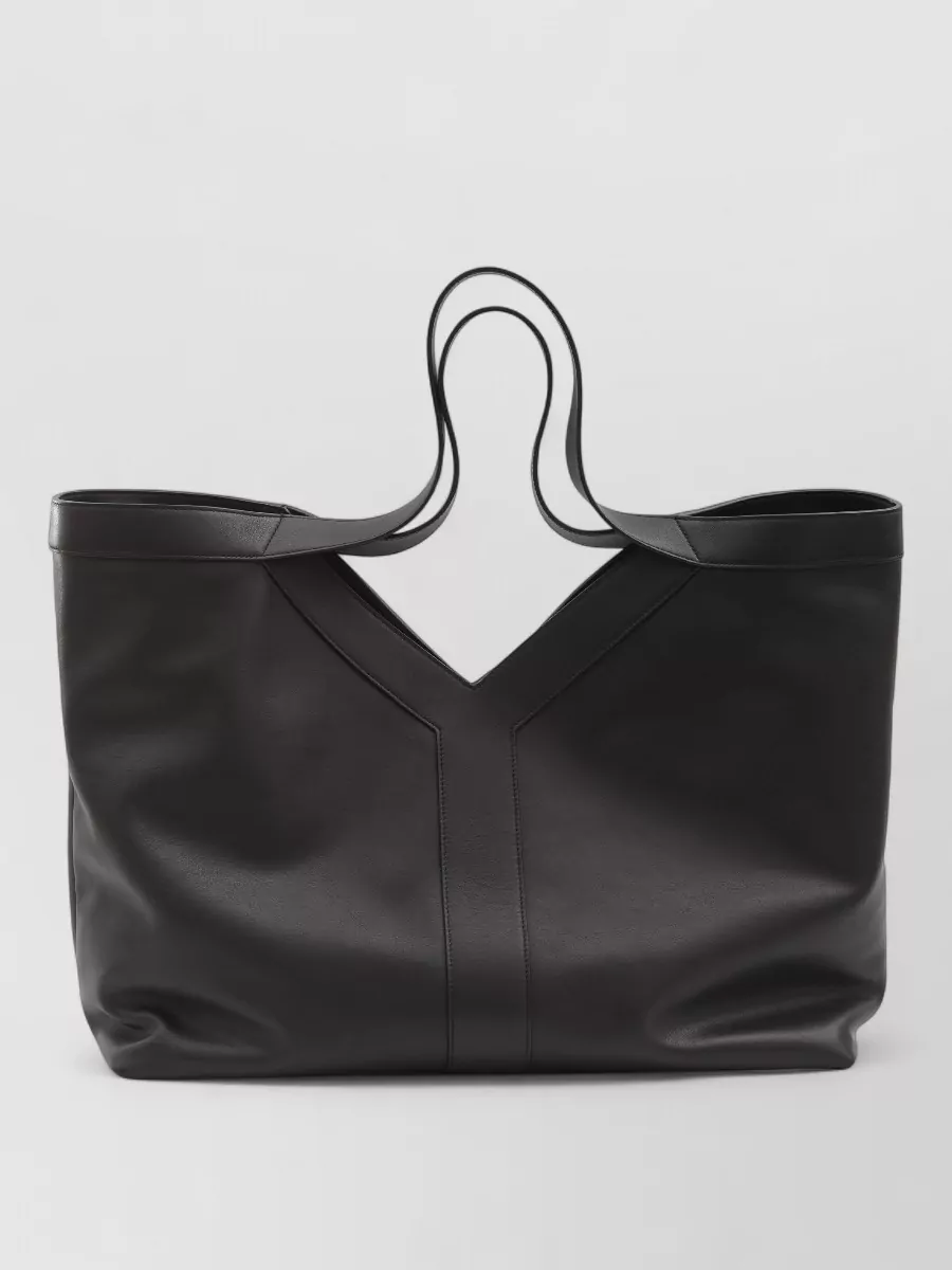 Saint Laurent Leather large tote bag — The oversized soft black Saint Laurent tote mirrors the outfit’s clean, architectural lines and luxury tier while adding a fluid counterpoint to the tailored silhouette.