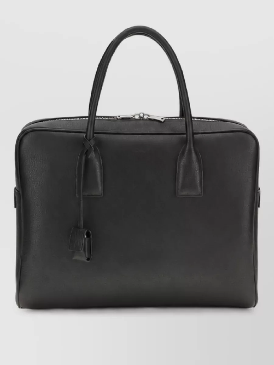 Saint Laurent Leather briefcase — The grained black Saint Laurent briefcase matches the outfit’s tailored, quiet-luxury intent and formality, adding a functional but discreet note that suits both office and evening settings.