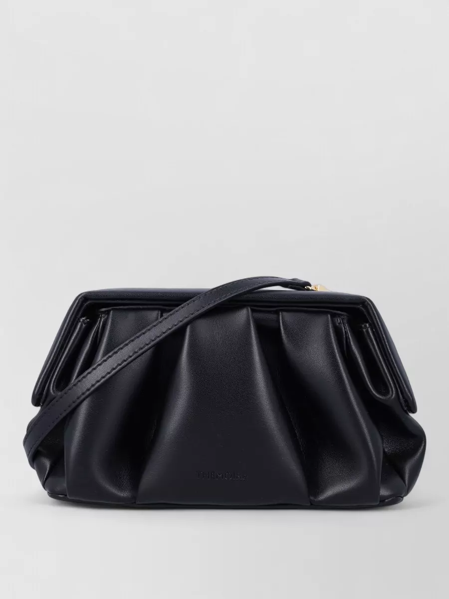 Themoiré Na vegan leather clutch bag — The black pleated Themoiré clutch sits in the same minimalist, quiet luxury space, its compact structure and soft volume echoing the dress’s gathered waist without disrupting the ink-black column effect.