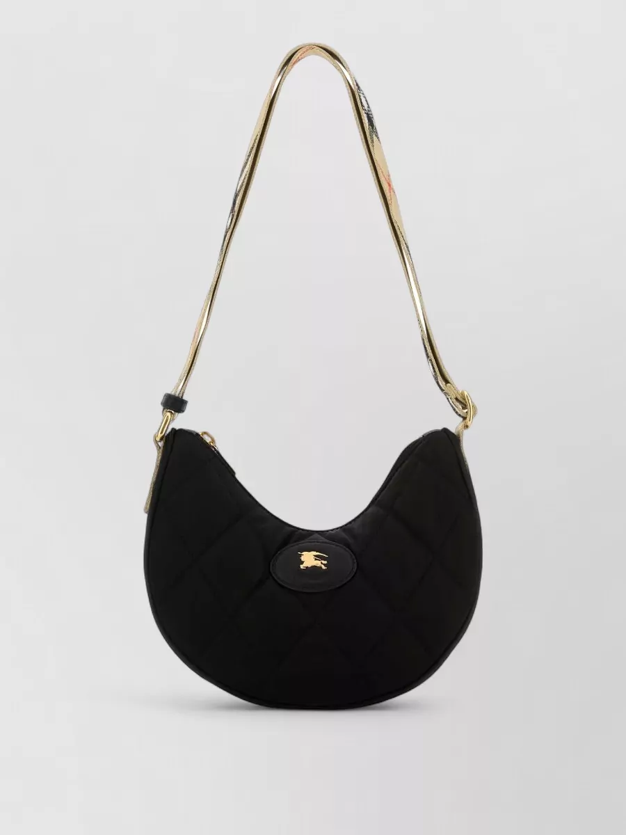 Burberry horseshoe nylon shoulder bag — The small Burberry check baguette reinforces the camel and check story at a dressier tier, matching the shorts and outerwear while staying compact and structured.