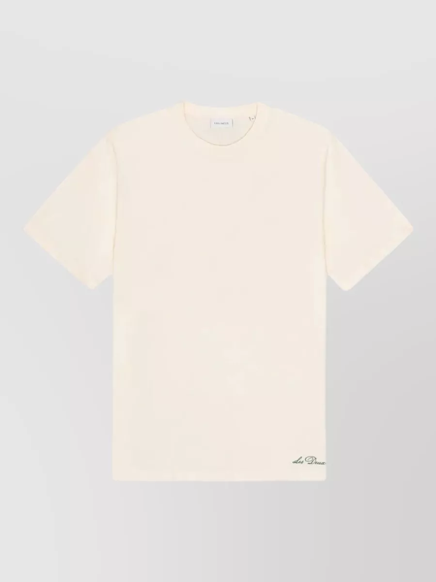 Les Deux Ben artist short-sleeve t-shirt — The warm beige open-knit cardigan mirrors the shorts’ soft neutrals and mesh texture, giving a relaxed Riviera-prep set that feels breezy yet more considered than a basic tee.