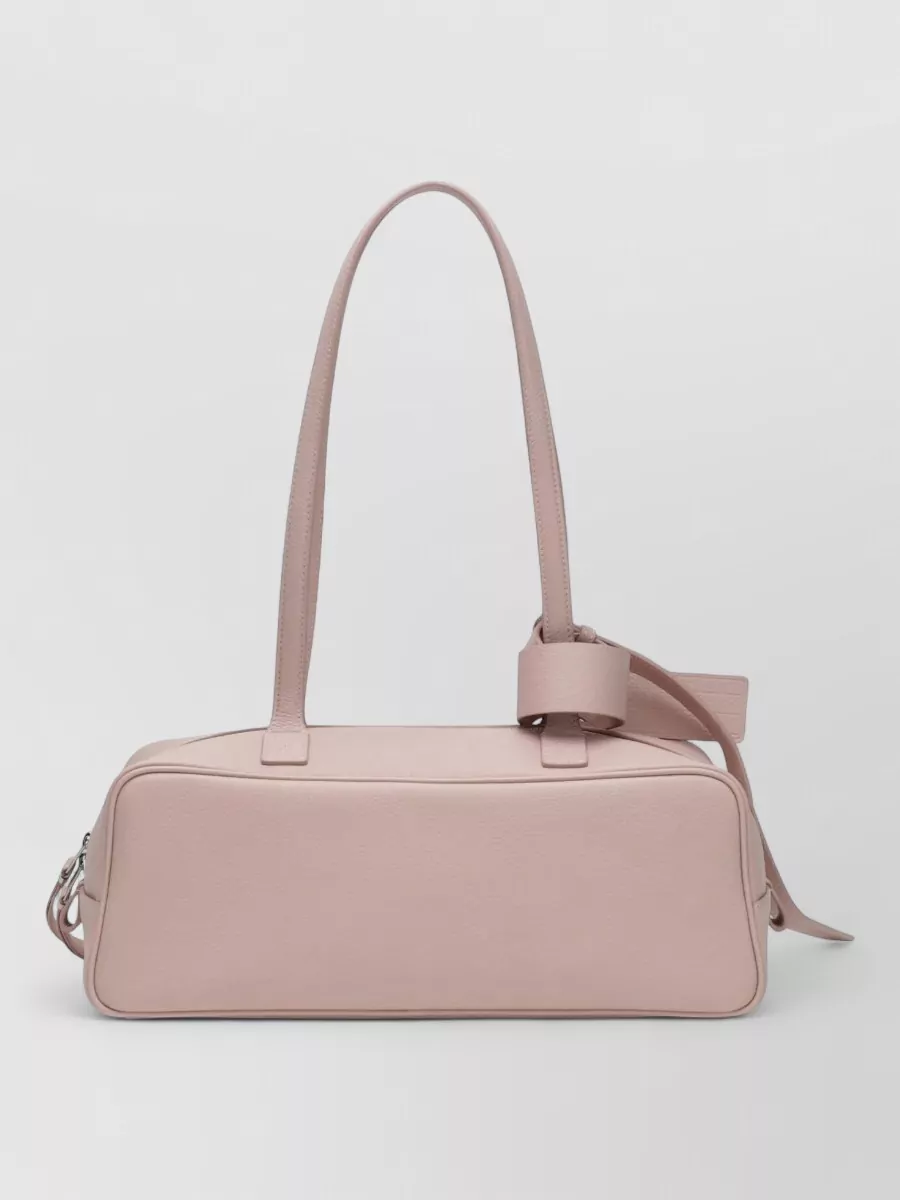 Balenciaga Na shoulder bag — The slim dusty-blush shoulder bag harmonises tonally with the tee, keeps the color story soft rather than bubblegum, and its quiet shape stays in the same luxury tier without shouting.