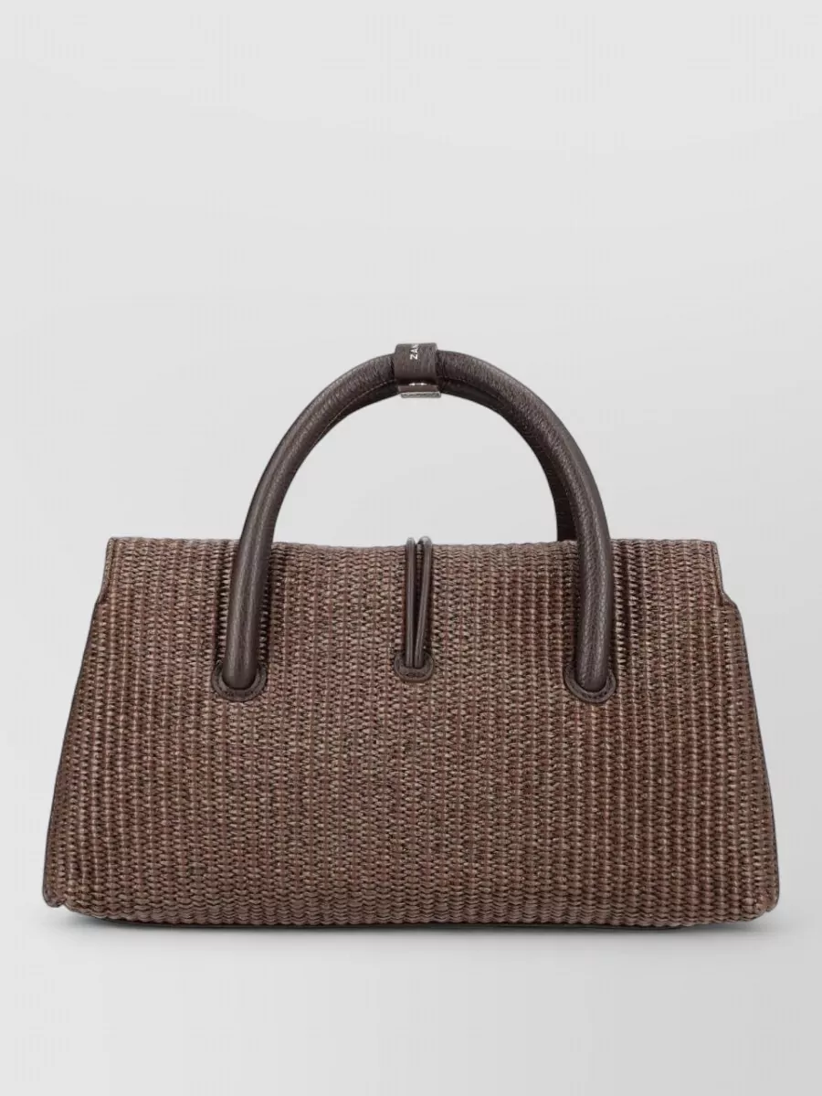 Zanellato Leather tote bag — The woven chocolate top-handle satchel mirrors the shorts and sandals in tone, adds subtle texture, and stays in a polished yet easy register that suits the minimalist outfit.