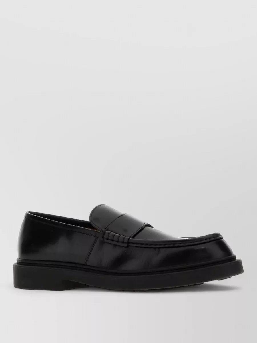 Jil Sander Leather loafers — The sleek black penny loafer matches the trouser’s formality and the shirt’s quiet rigor, grounding the outfit with polished structure rather than casual sneaker ease.