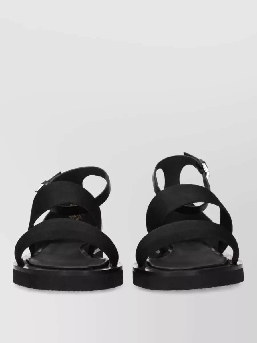 Max Mara Fabric sandals — The flat black ankle-strap sandal keeps the palette seamless, the mood minimal and the formality easy, visually lightening the long wide-leg trouser for warm-day wear.