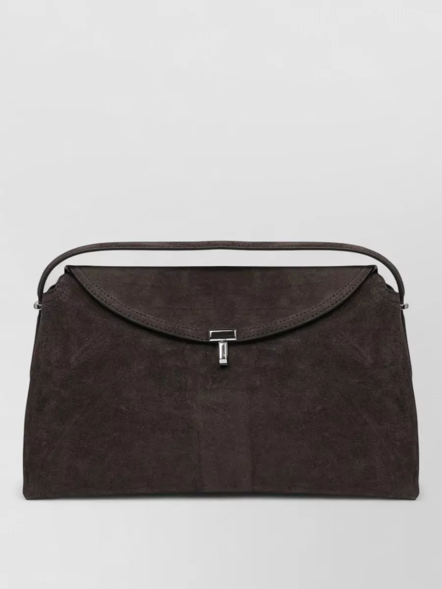 Totême Leather top handle clutch bag — The Totême dark chocolate suede top-handle keeps the palette tonally aligned with the boots while maintaining a minimalist, high-tier mood that feels discreet rather than logo-driven.