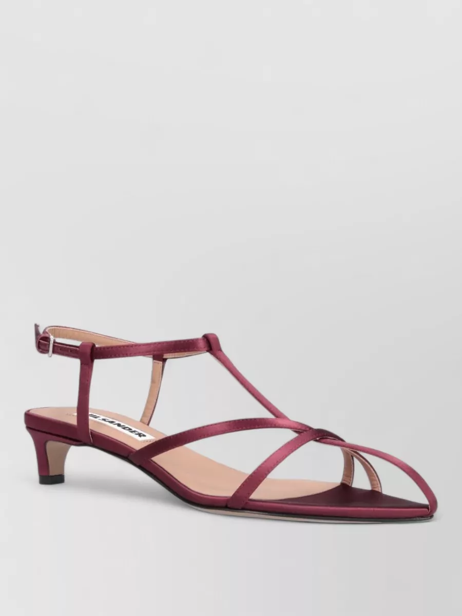 Jil Sander Leather cage sandals — The Jil Sander deep wine kitten-heel slingback is refined and comfortable, echoing the bag’s rich reds without competing, and its minimalist straps complement the Prada dress’s delicate bow detail.