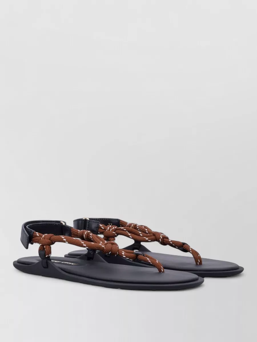 Miu Miu Thong sandals — The navy and chestnut flat braided sandals mirror the skirt’s blues and earthy tones while keeping the mood relaxed and genuinely day-into-evening summer appropriate.