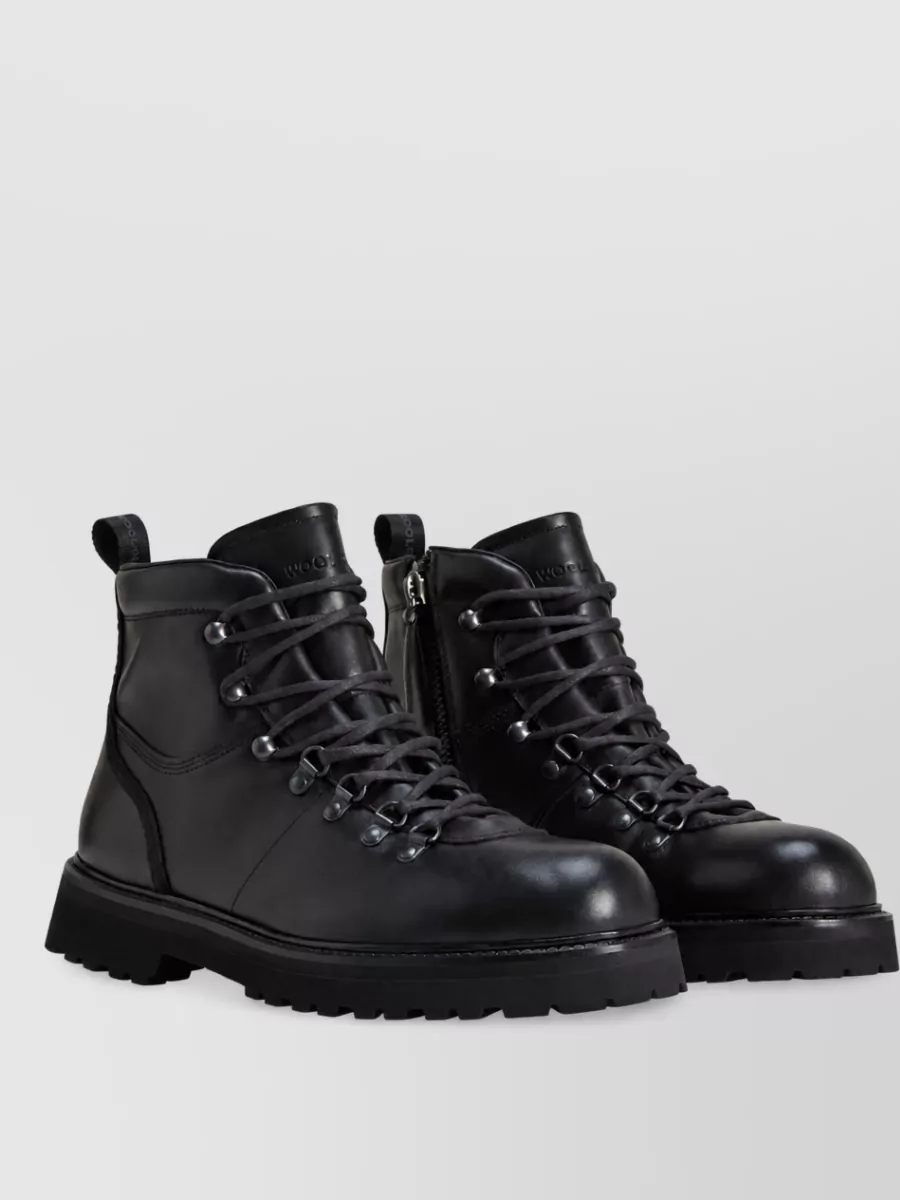 Woolrich Hiking boots — The black Woolrich hiking boots echo the outerwear’s utilitarian feel, adding sturdy winter function while keeping the look clean and in the same premium performance tier.