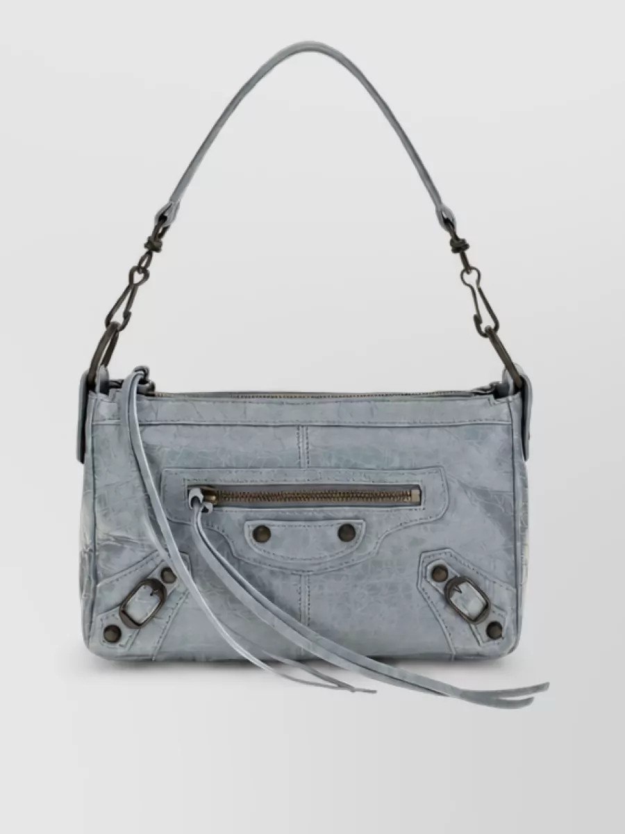 Balenciaga Na lamb leather clutch bag — The slate blue-grey moto shoulder clutch stays in the same cool blue family as the cropped outer shirt while adding subtle texture and hardware, tying the palette together without overwhelming the architectural silhouettes.