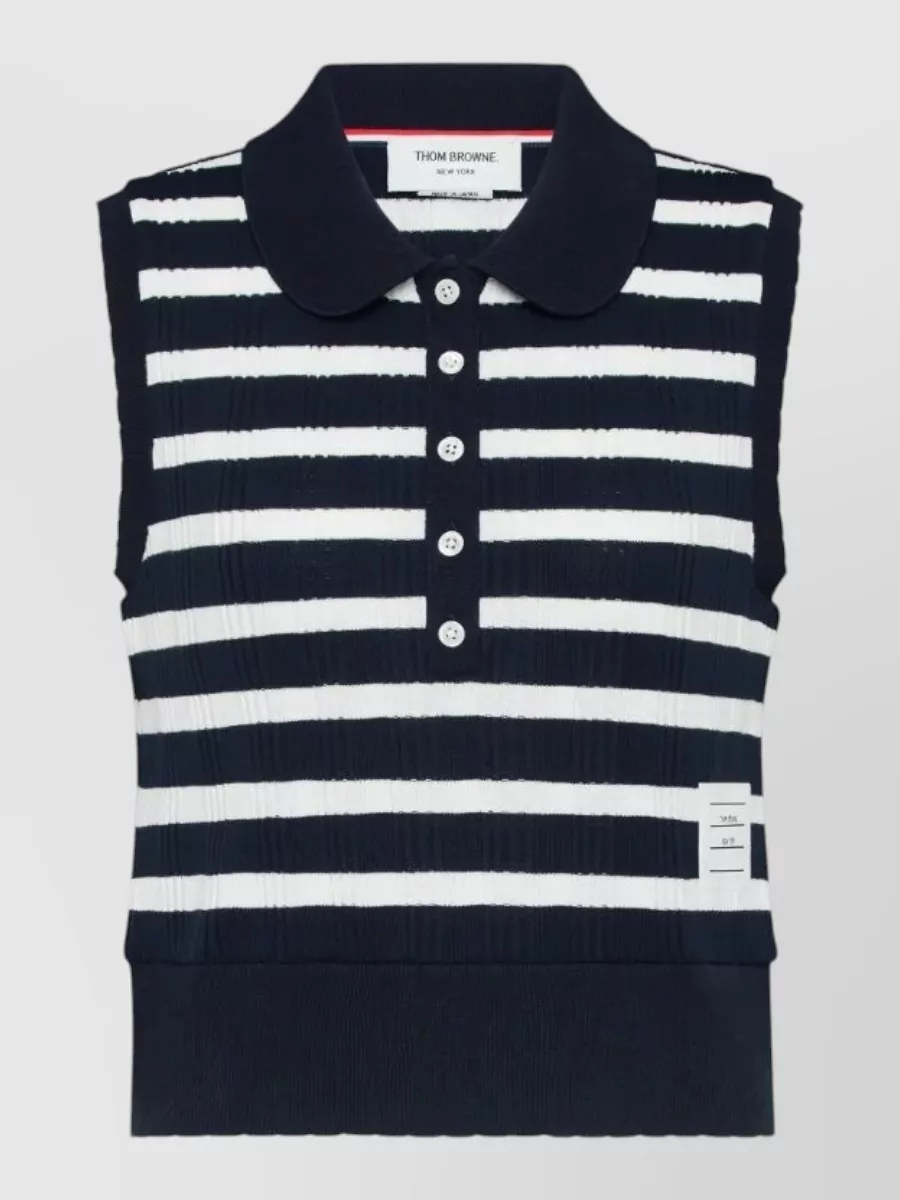 Thom Browne Striped ribbed polo top — The cropped sleeveless Breton-stripe polo in navy and white mirrors the skirt’s tennis-prep energy, keeps the palette tight, and balances the mini’s volume with a sharp, waist-defining proportion for an SS, sport-preppy set look.