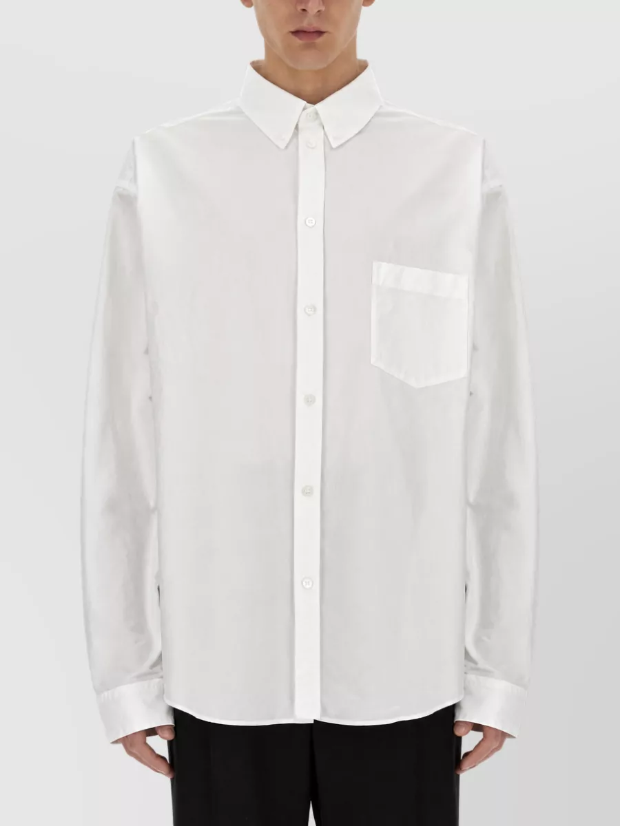 Balenciaga Large-fit shirt — The Balenciaga poplin shirt keeps the front minimal yet aligns with the trouser’s subversive twist at the hem, maintaining a house-consistent, tailored mood that suits formal evening settings.