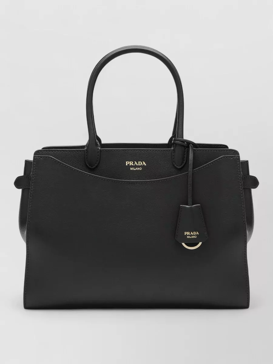 Prada Na shoulder bag — The Prada structured top-handle bag matches the outfit’s sharp tailoring and black palette, providing a high-tier, polished finish that works seamlessly from meetings to dinner.