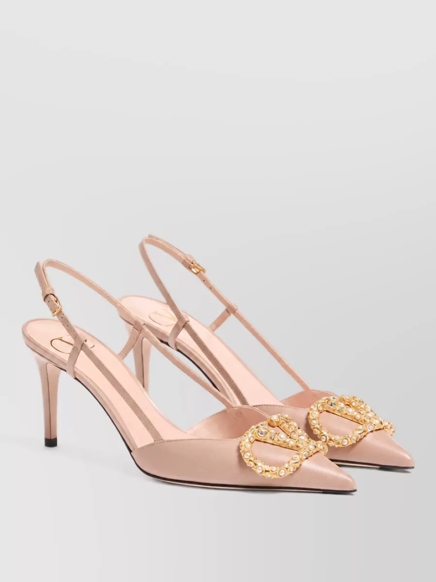 Valentino Garavani Leather slingback pumps — The blush-nude Valentino Garavani slingback stiletto echoes the romantic mood, maintains evening formality, and visually lengthens the leg against the ivory skirt without adding heaviness.
