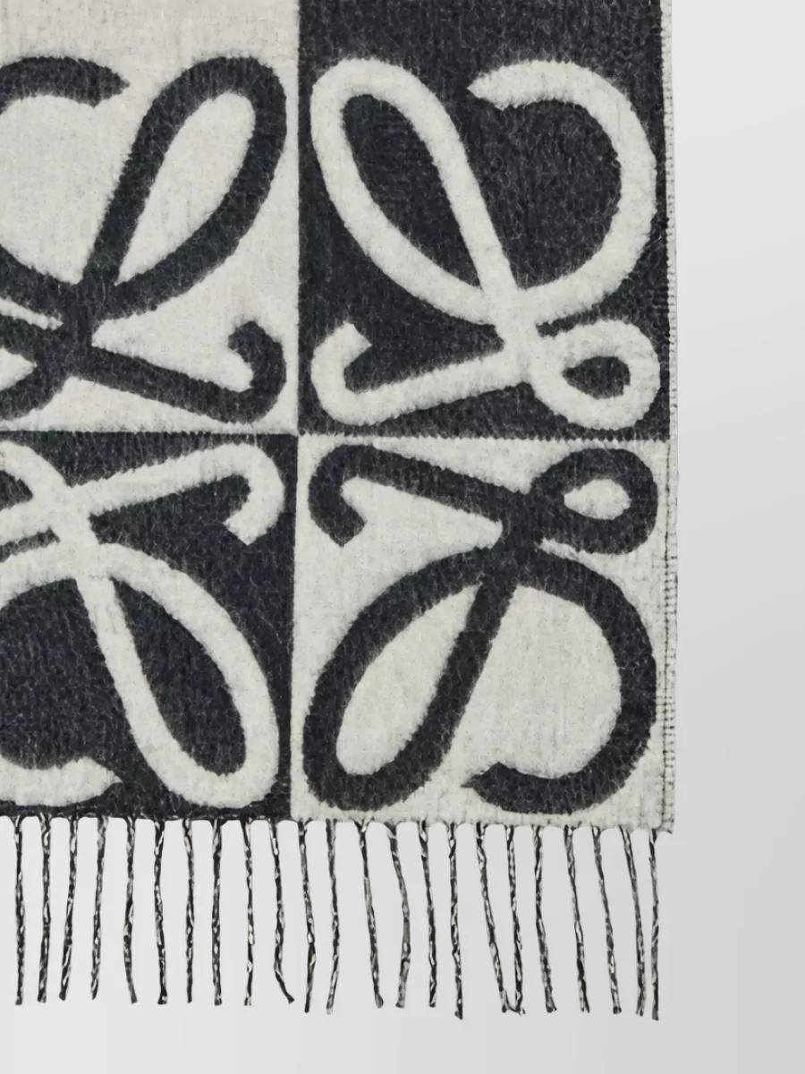 Loewe Wool cashmere scarf — The monochrome Loewe scarf introduces a graphic black-and-ivory note that resonates with the trousers’ palette, adding winter texture while staying within the quiet luxury language.