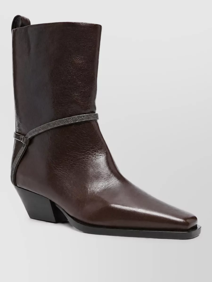 Brunello Cucinelli Leather boots — The Brunello Cucinelli black knee-high block-heel boots are formal enough, echo the coat’s polished black palette, and extend the long line of the shirtdress without competing with its tailoring.