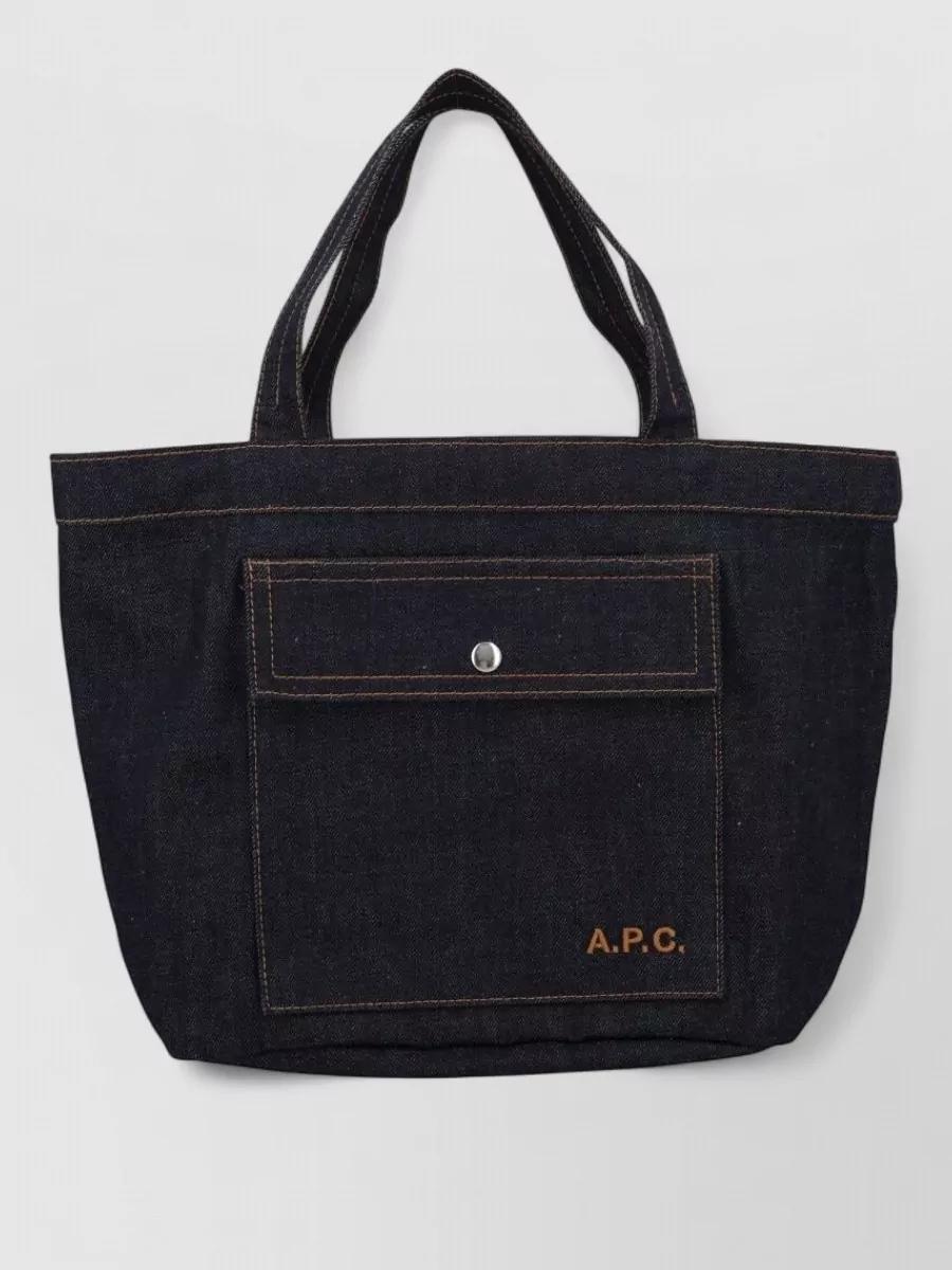 A.P.C. Medium cotton logo-embroidered tote bag — The structured dark-raw denim A.P.C. tote keeps the outfit in a refined workwear universe, its deep indigo tying into the jacket without competing with the washed textures.