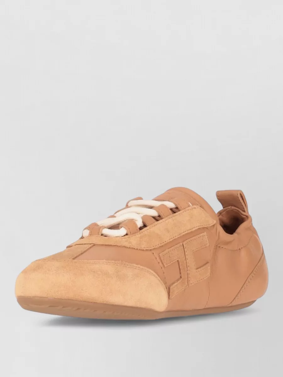 Elisabetta Franchi Leather lace-up shoes — The tan Elisabetta Franchi sneakers stay in the same luxe-athleisure family, echo the jogger’s logo polish, and keep the blush-and-neutral palette refined rather than overtly sporty.
