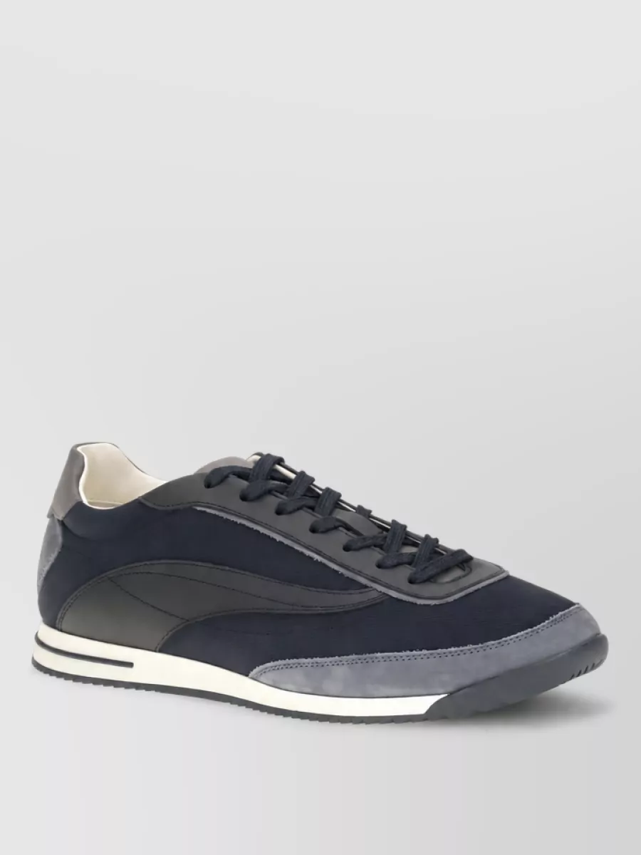 Brunello Cucinelli Suede leather lace-up low-top sneakers — The streamlined navy runner reads refined rather than overtly sporty, echoing the jacket’s quietly technical energy and tying the blue palette together with a clean, city-appropriate finish.