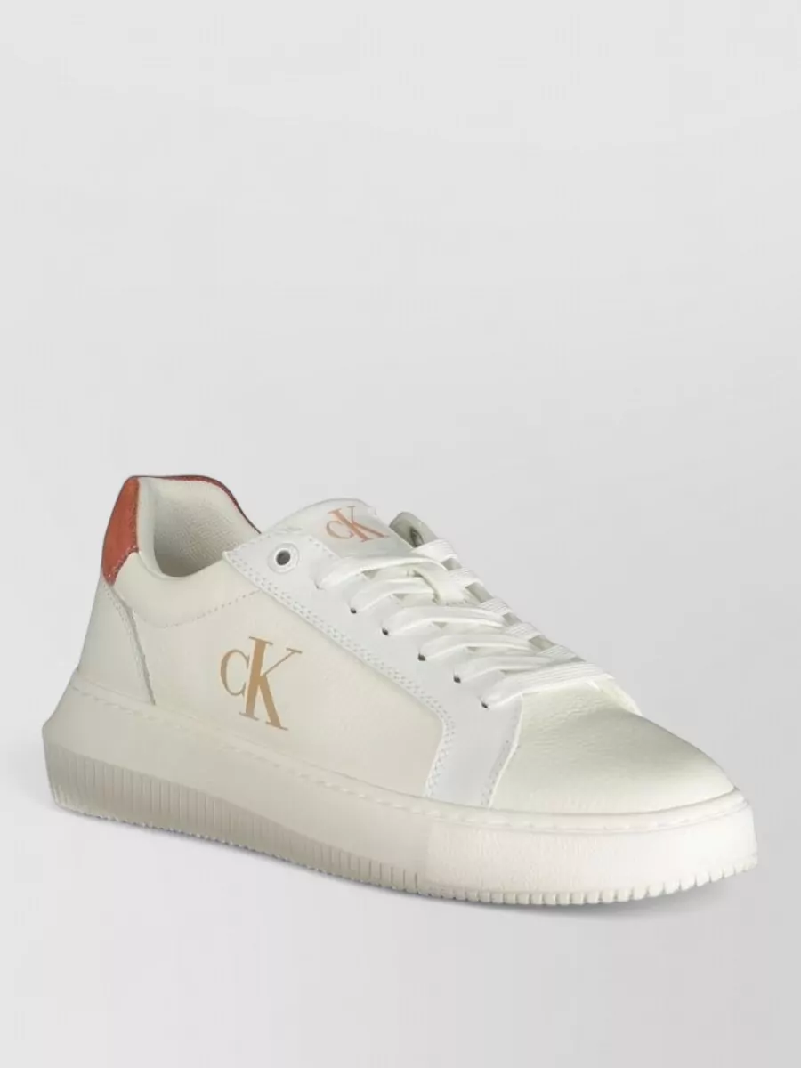 Calvin Klein Leather platform lace-up sneakers — The off-white Calvin Klein platform sneaker with a tan heel tab lightens the outfit, references the jacket’s cognac tone, and keeps the vibe sporty yet clean.