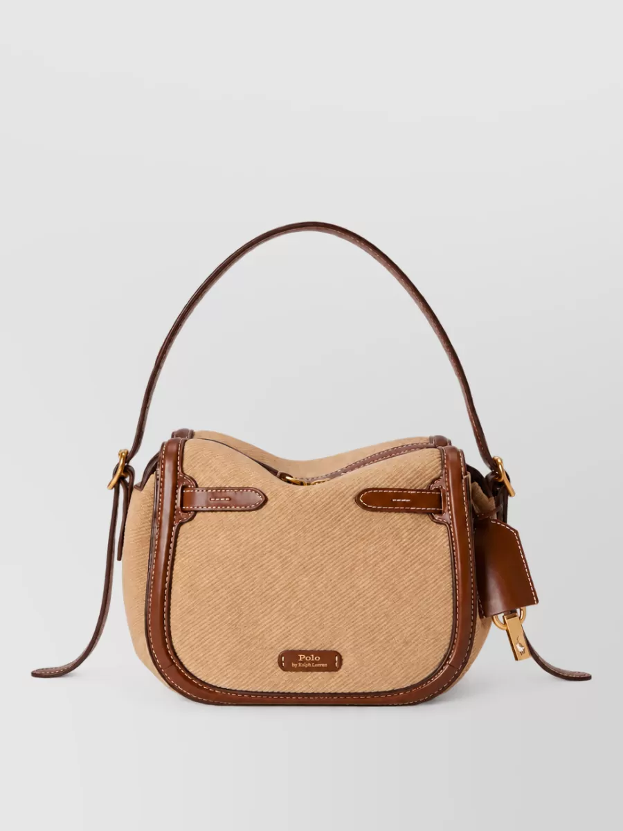 Ralph Lauren Leather shoulder bag — The camel and chocolate shoulder bag introduces warm equestrian notes that sit perfectly with the cream sweater’s quiet-luxury mood and bridge the navy bottom and neutral top.