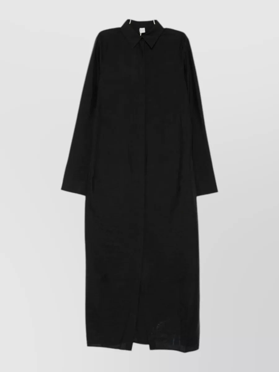 Totême Silk long-sleeve maxi dress — The black Totême maxi shirt dress mirrors the trench’s architectural minimalism and creates a clean column that layers seamlessly under the short black trench for a coherent, modern uniform.