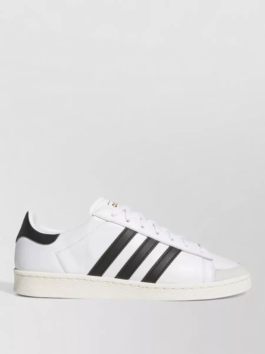 Adidas Originals Low-top sneakers — The white Adidas court sneaker with black stripes adds crisp contrast against the grey joggers and black top, matching the sporty-preppy mood while keeping the formality polished for off-duty city wear.