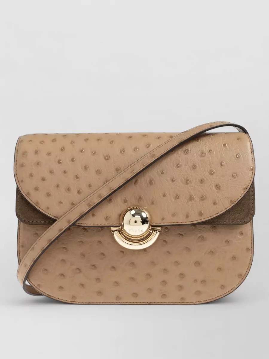 Furla Sfera small leather cross-body bag — The camel-beige Furla flap cross-body stays within the warm neutral palette, adds quiet Italian gloss, and harmonises with the caramel dress and tan collar without competing with the heritage boots.