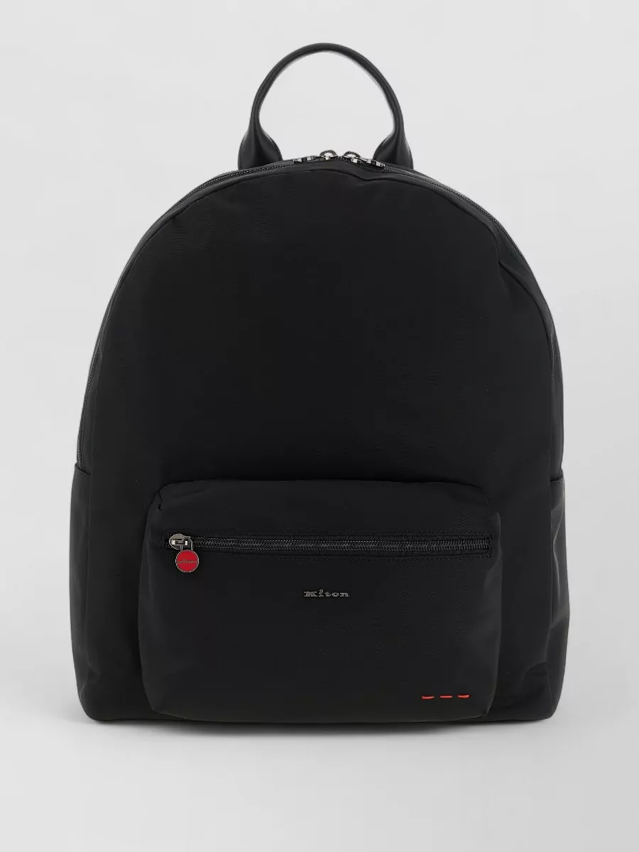 Kiton Technical canvas backpack — Kiton’s black backpack with subtle red detailing quietly echoes the knit’s red zip pull, keeps everything in the same luxury tier, and suits the polished-casual mood.