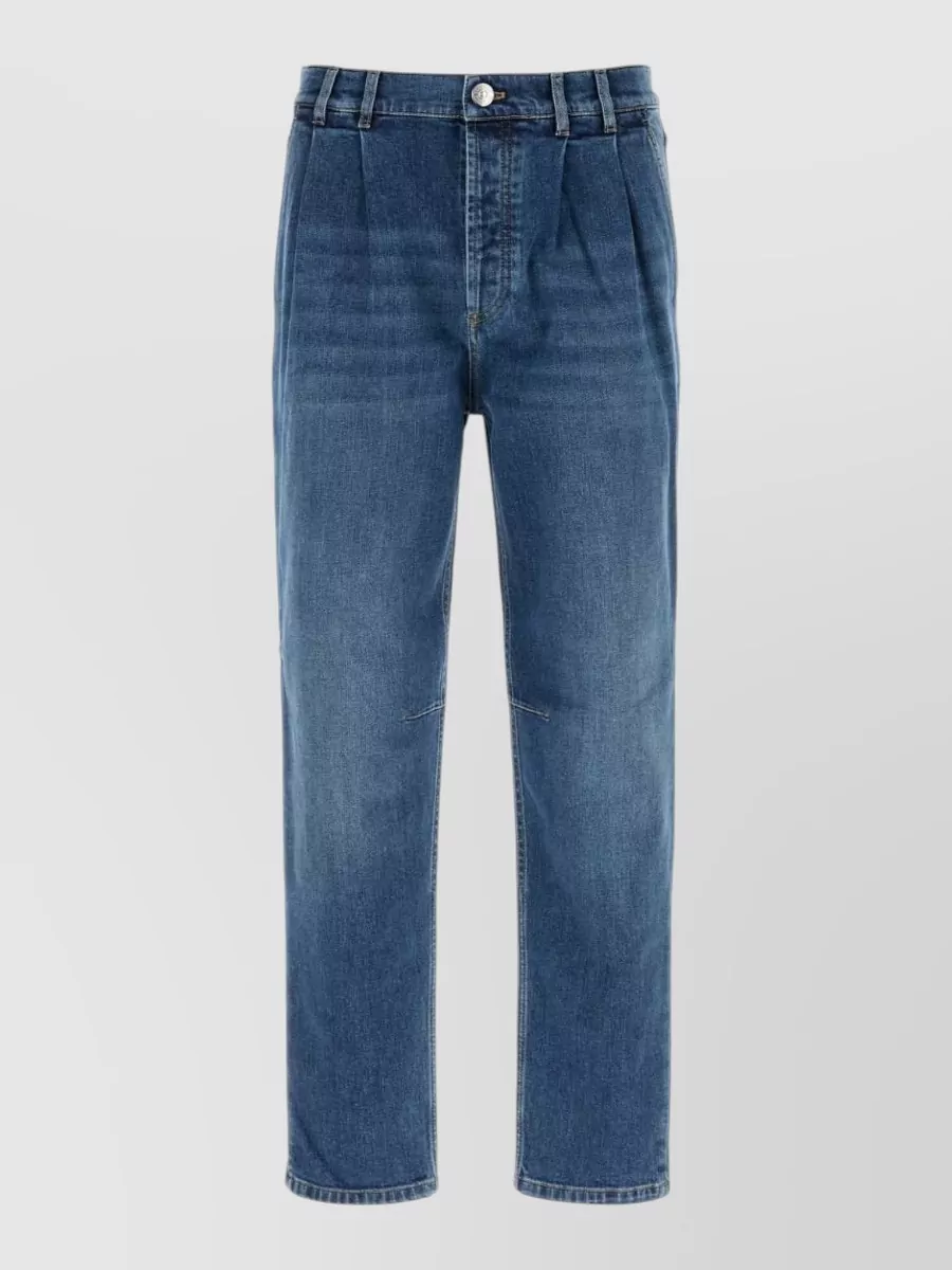 Brunello Cucinelli Denim jeans — The pleated, tapered indigo denim reads closest to a tailored trouser, matching the shirt’s slim, sartorial line and keeping the double-denim palette refined rather than casual.