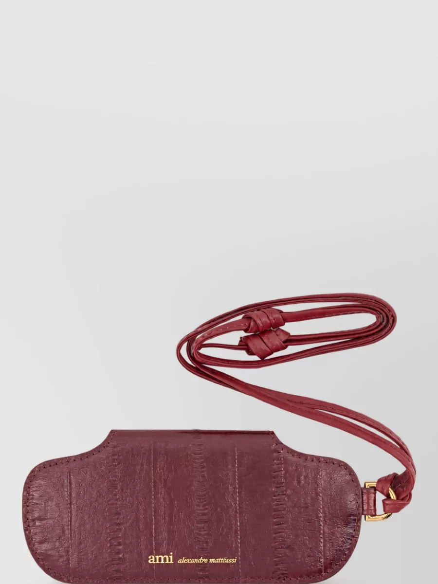 Ami Paris Leather glasses case charm — The Ami Paris deep-burgundy belt bag introduces a rich accent that still reads minimalist and quietly luxurious, sitting neatly at the waist to define the high-rise denim without overwhelming the palette.