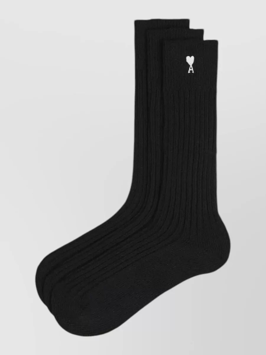 Ami Paris Ribbed logo socks set of three — The black Ami socks quietly tie in with the polo and black bag, giving a subtle designer touch while keeping the palette tight and minimal around the white shorts and sneakers.