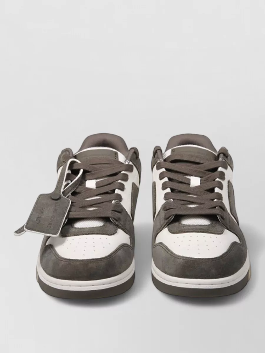 Off-White Leather paneled low-top sneakers — The white and brown court sneakers echo the shirt’s chestnut accents and keep things sporty, grounding the dark denim with a soft neutral contrast that fits the streetwear-preppy brief.