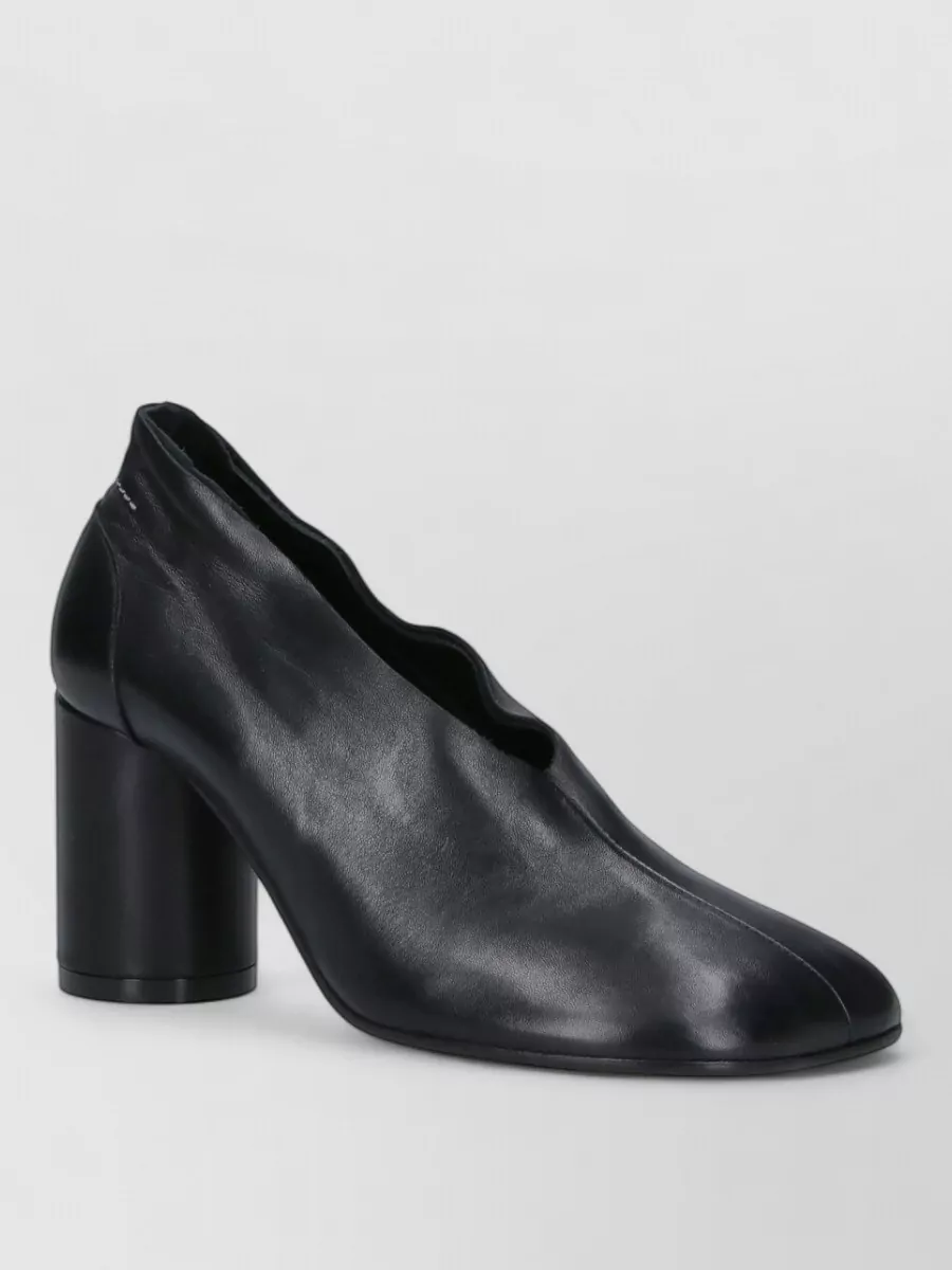 Mm6 Maison Margiela Leather high heel pumps — The sculpted black block-heel pump is minimal yet assertive, matching the tailored trouser’s formality while echoing the Margiela language in a walkable, city-ready heel.